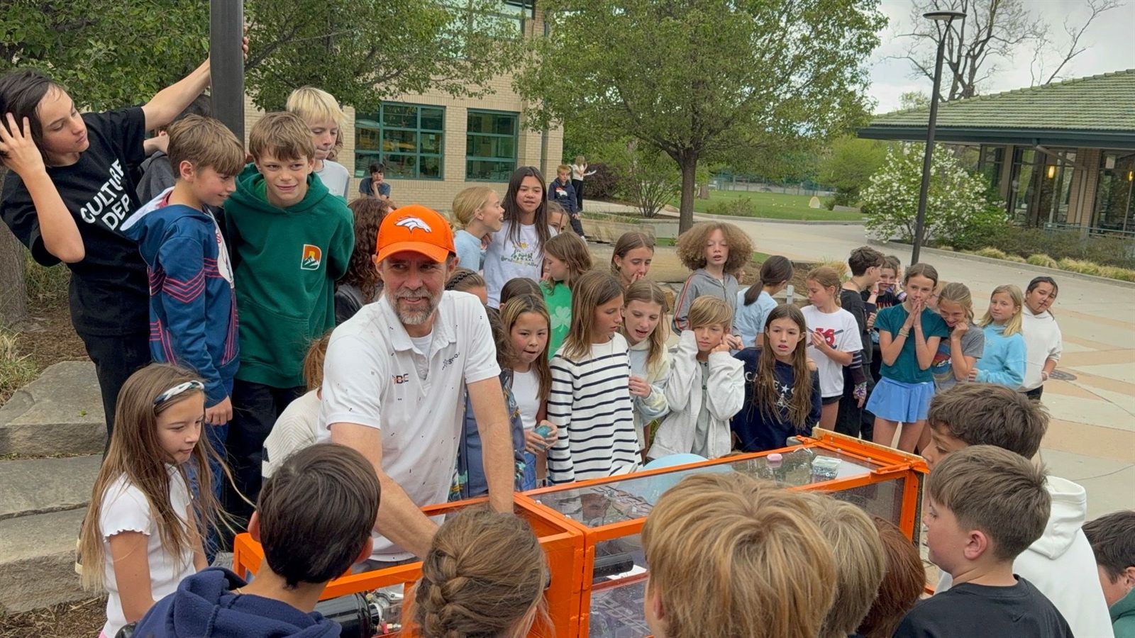 Daniel Burgess demonstrating a hail impact test machine to students at a Front Range school event, June 2026