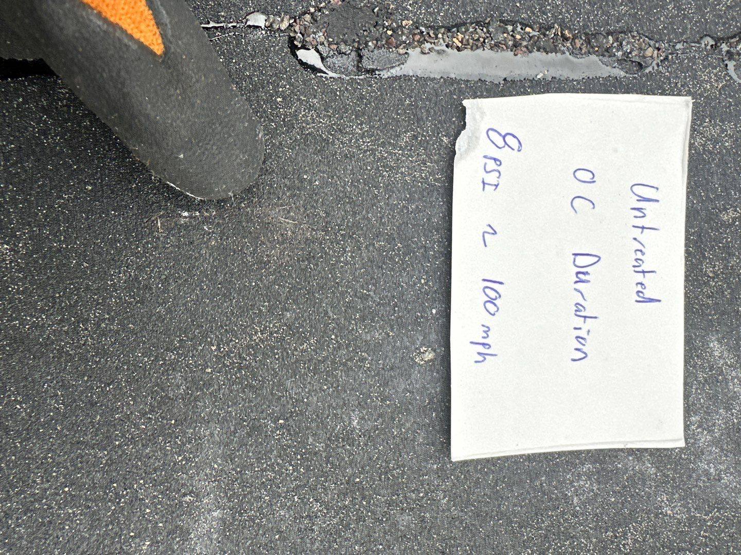 Untreated Owens Corning Duration shingle with labeled test card showing a scuffed bare patch after the same simulated-hail bench test by Bailey Roofing, April 2026