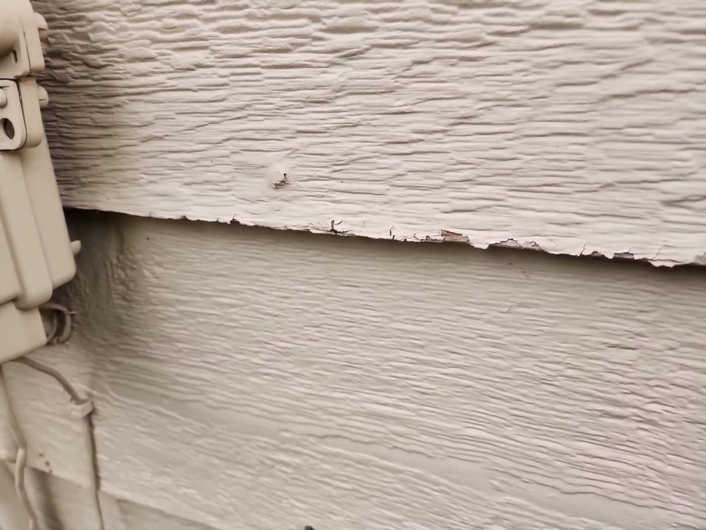 Chipped and dented siding from hail on a Centennial home