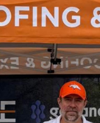 Daniel Burgess of Bailey Roofing at the company booth during a 2026 community hail-cannon demonstration